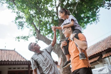 Asyalı baba sırtında mutlu bir kız çocuğu büyükbabayla boş zamanlarının tadını çıkarıyor.