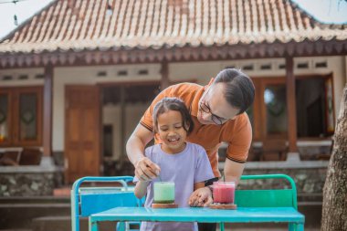 Asyalı baba, açık havada kadın çocukla bağ kuruyor.