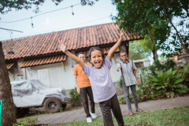 Neşeli genç çocuk, babası ve büyükbabasıyla eğlenirken elini kaldırıyor.