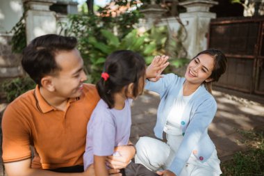 Asyalı anne kızıyla beşlik çakıyor.