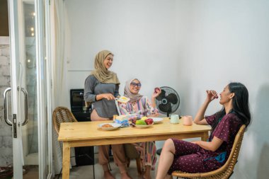 Aile üyeleri sıcak ve rahat bir mutfak atmosferinde keyifli bir yemeğin tadını çıkarırlar.