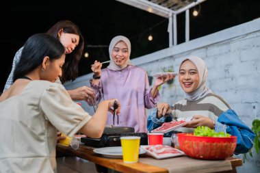 Bir grup arkadaş keyifli bir şekilde açık hava ortamında çeşitli lezzetli yemekleri paylaşıyorlar.