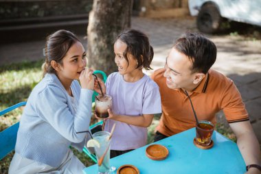 Asyalı ebeveyn, bir kafede takılarak kızlarıyla bağ kuruyor.