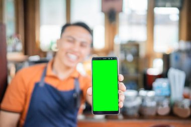Boş ekran telefonu tutan erkek baristanın seçici odağı