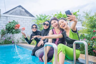 Neşeli ve eğlenceli bir an. Mutlu bir şekilde havuz kenarında selfie çekiyorlar.