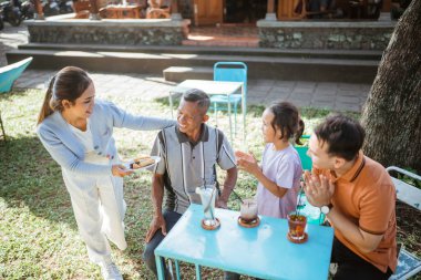 Asyalı geniş aile, bir restoranda öğle yemeği yemek için zaman harcıyor.