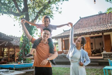 Genç Asyalı ebeveynler kızlarıyla bahçede eğleniyorlar.