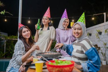 Bir grup arkadaş dışarıda neşeli bir kutlama yapıyor. Yiyecek ve içeceklerle.