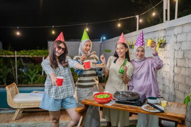 Dostlar renkli şapkalar ve hoş içkilerle neşeli bir toplantının tadını çıkarırlar.