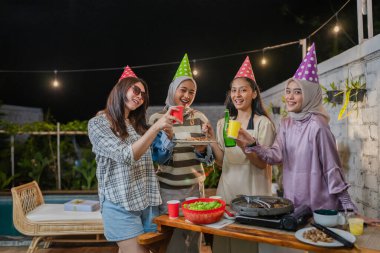 Dört arkadaş birlikte sevinçle kutlama yapıyor, içkilerini paylaşıyor ve yürekten gülüyorlar.