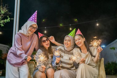 Neşeli bir arkadaş toplantısı. Maytap ve renkli şapkalarla.