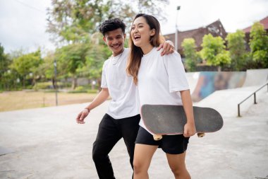 İki yakın arkadaş parkta kayarken keyifli bir anı paylaşıyorlar.