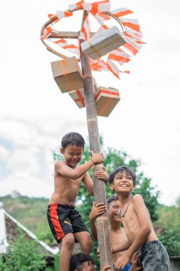 Gülen çocuklar özgürlüklerini kutlamak için betel fındık tırmanma yarışmasında mutlu bir şekilde tırmanıyorlar.