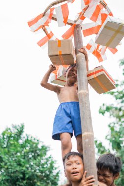 Betel 'in ceviz tırmanma yarışması sırasında arkadaşlarının omzunda duran çocuk ödül kutusunu asıyor.
