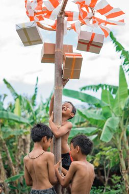 Endonezya 'nın bağımsızlığı anısına düzenlenen Pinang tırmanma yarışmasında üç çocuk birbirine yardım etmeye çalışıyor.