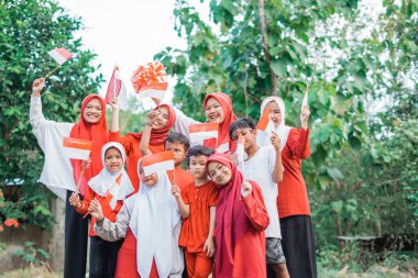 Bağımsızlık kutlamaları sırasında ellerinde küçük Endonezya bayrakları tutan kırmızı ve beyaz özellikleri olan bir grup genç kadın ve erkek