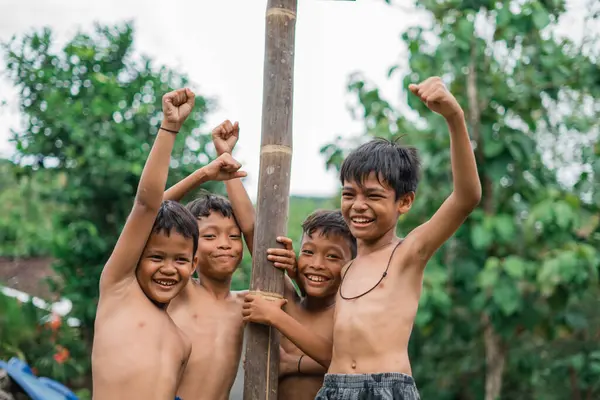 Çocuklar betel fındık tırmanma yarışmasında ayakta dururken heyecanlanıp gülüyorlar.