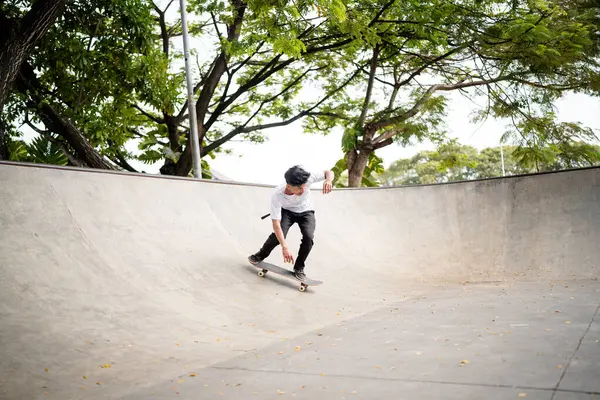 Yetenekli bir patenci etkileyici yeteneklerini parktaki beton kase alanında sergiliyor.