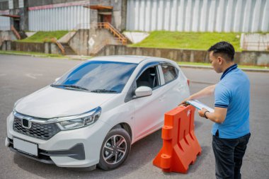 A traffic officer is checking a vehicle at a roadside checkpoint with safety barriers in place clipart