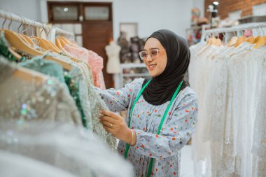 Bir moda tasarımcısı canlı bir butikte çarpıcı elbiseler sergiliyor, yaratıcılık ve tarz sergiliyor.