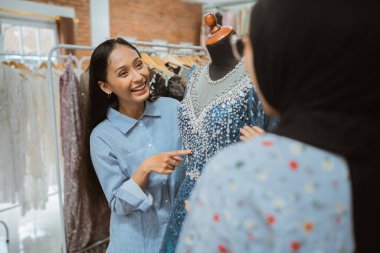 Yetenekli bir tasarımcı, hevesli ve memnun bir müşteriye güzel bir elbise sergiler.