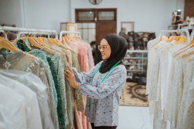 Bir kadın modaya uygun kıyafetleri şık bir butikte gezer.