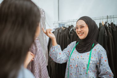 Neşeli genç bir kadın butikte çeşitli şık kıyafet seçeneklerini keşfetmekten mutluluk duyar.