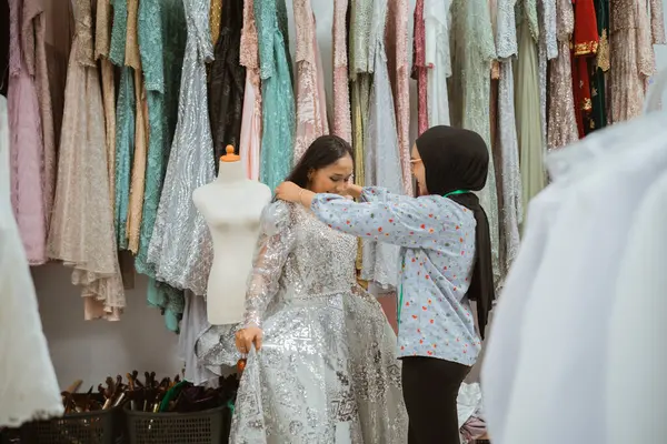 İki genç kız neşeyle kumaşlarla dolu canlı bir butikte zarif elbiseler keşfediyor.