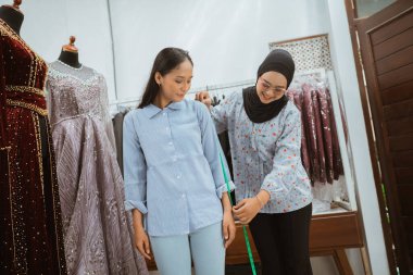 Bir moda tasarımcısı müşterisini yüksek kaliteli bir terzilik stüdyosuna mükemmel uyacak şekilde ölçer.