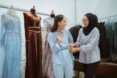 Kadınlar zevkle ve heyecanla şık bir butik ortamında güzel elbiseler giyerler.