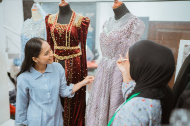 Büyüleyici bir butik ortamında, iki kadın coşkuyla muhteşem gece elbiselerini tartışıyor.