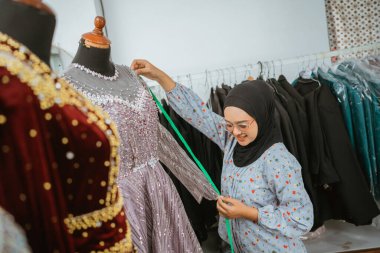 Yetenekli bir terzi, düzenli atölyesine geleneksel bir elbiseyi dikkatlice yerleştiriyor.