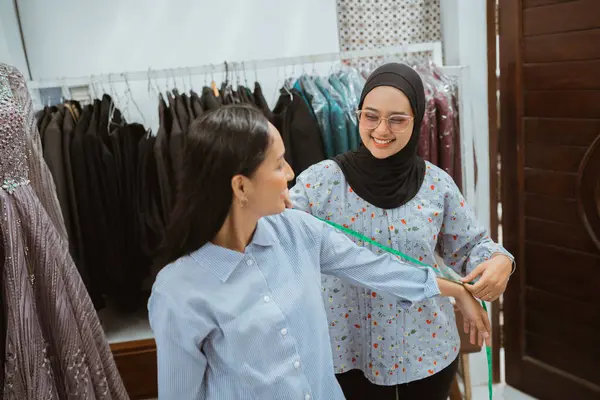 Kadınlar şık bir butik ortamda elbise provasında işbirliği içinde çalışıyorlar.