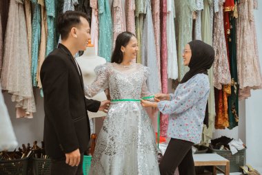 Yetenekli bir terzi moda dolu canlı bir butikte gelinlere çok yakışır.