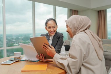 İki hırslı kadın yenilikçi iş fikirlerini parlak ve modern bir ofiste tartışıyor.