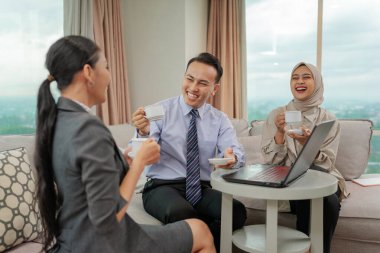 Üretken bir iş toplantısı sırasında birlikte kahvenin tadını çıkaran üç deneyimli profesyonel.