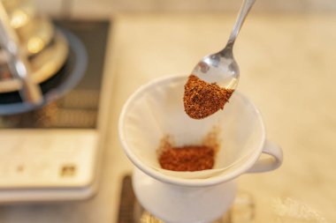 Mükemmel demleme işlemi için bir kaşık dolusu öğütülmüş kahve damlatıcıya konur.