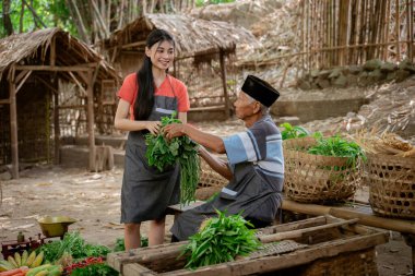 Yaşlı bir çiftçi ile genç bir kadının kırsal kesimde taze ürünler arasında canlı bir etkileşim..