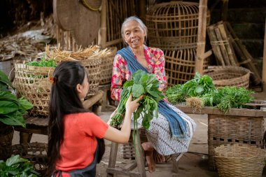 İki kadın canlı bir pazarda taze sebzeleri paylaşıyor. Toplumun ruhunu ve kültürel değerlerini sergiliyorlar.
