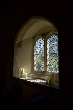   Pencerenin her iki tarafında üç beyaz mum bulunan bir kilise penceresi pencere pervazının üstünde ve altında duvar siyahtır, kopya alanı için idealdir, Ringmer Kilisesi, Ringmer, Doğu Sussex, Birleşik Krallık