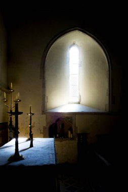   Işık kemer şeklinde bir kilise penceresinden geçiyor ışık kilise mumlarına ve şamdanlara düşüyor, ışık dramatik bir atmosfer yaratıyor, pencerenin altında ve üstünde duvar siyah, kopyalama alanı için ideal, Ringmer Parish kilisesi, halka