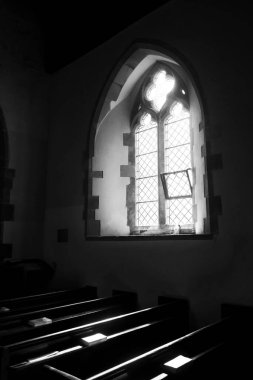  Kilise içi, iki kemerli kilise penceresinden akan ışık, pencerenin önünde üzerinde İncil olan kilise sıraları var. Ön planda bir kartal şekilli ahşap kürsü var. Işık dramatik bir şekilde gotik bir atmosfer yaratıyor.