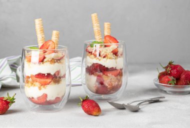 Çilekli tatlı, bisküvi, mascarpone peyniri, badem ve gri arka planda kurabiye tüpleri.