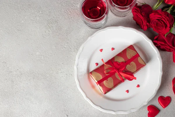 礼物包在白盘上 红玫瑰和两杯酒杯酒放在小桌子上 情人节的概念 — 图库照片