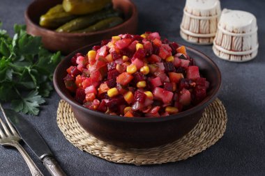 Geleneksel pancar, patates, havuç, mısır, turşu, soğan ve sebze yağından oluşan salata salatası koyu gri arka planda. Vejetaryen yemeği.