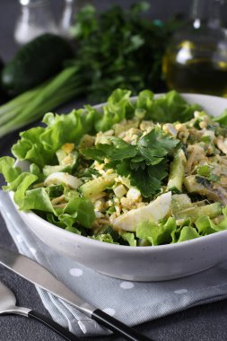 Kalamar, salatalık, haşlanmış yumurta ve peynirli salata yeşil marul yapraklı, dikey formatta.