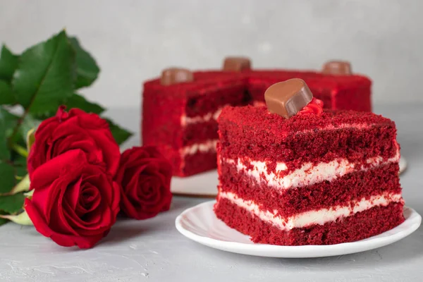 蛋糕红色天鹅绒与切块的前景和一束灰色背景的红玫瑰 — 图库照片