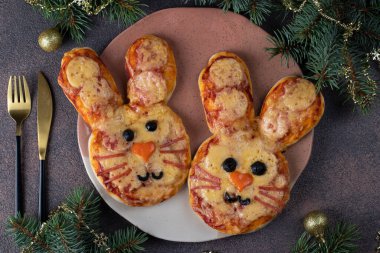 Domates soslu, salamlı, peynirli, zeytinyağlı, siyah zeytinli ve fesleğenli tatlı tavşanlı pizza. 2023 Yeni Yıl için yemek fikri