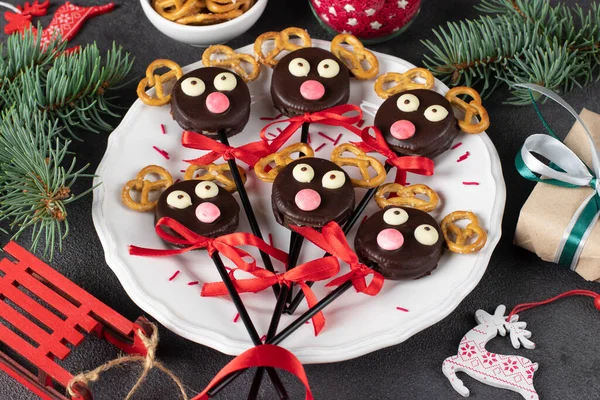 Cake pops Santa\'s reindeers made from cookies in chocolate and crackers on white plate, Close up