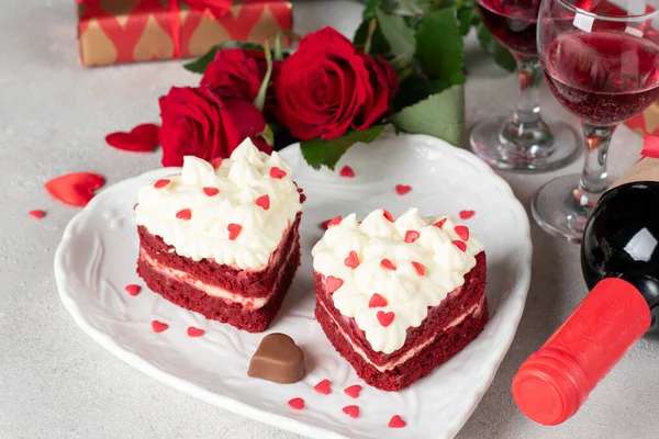 Cakes Red velvet in the shape of hearts on white plate, roses and bottle wine for Valentines Day